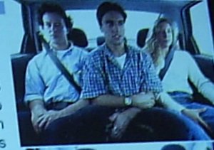 Tres passageiros sentados no banco de tras de forma desconfortavel